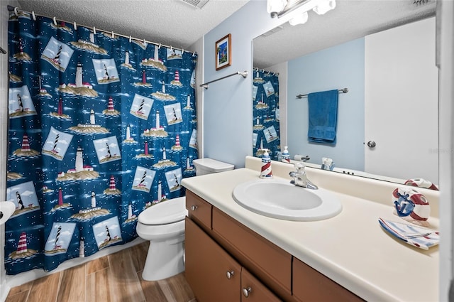 bathroom featuring vanity, hardwood / wood-style flooring, a textured ceiling, and toilet