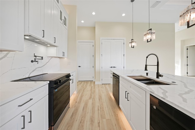 kitchen featuring white cabinetry, sink, hanging light fixtures, light stone counters, and black appliances