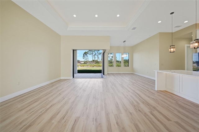 unfurnished living room featuring a raised ceiling, ornamental molding, and light hardwood / wood-style floors