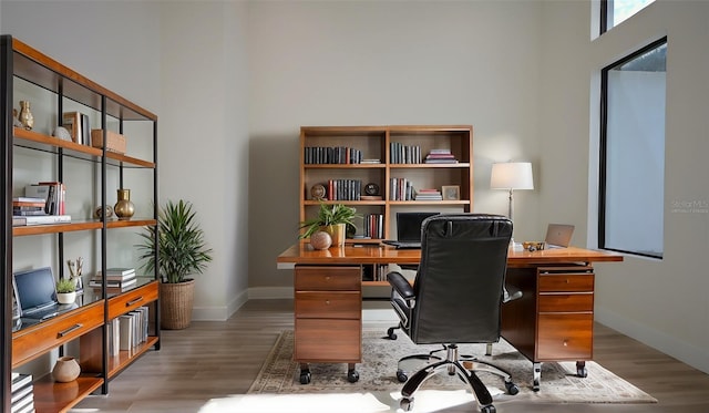 home office featuring wood-type flooring and a towering ceiling