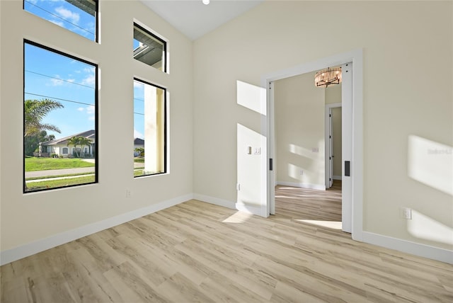 unfurnished room featuring a chandelier and light wood-type flooring