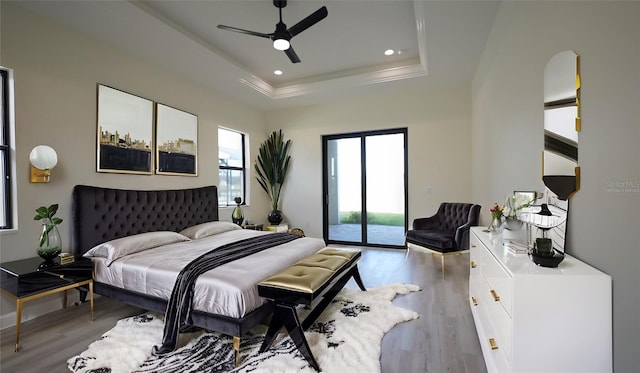 bedroom featuring ceiling fan, a raised ceiling, light hardwood / wood-style flooring, and access to outside