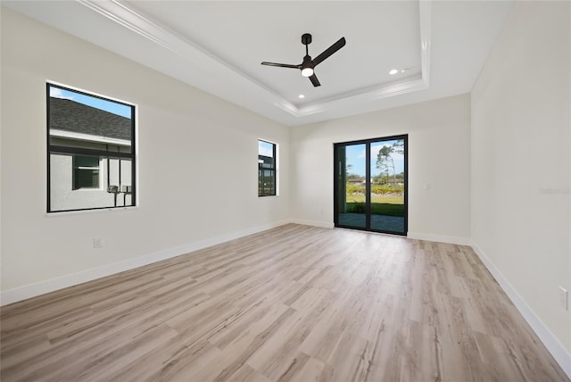 spare room featuring a raised ceiling, ceiling fan, and light wood-type flooring