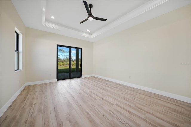 unfurnished room with ceiling fan, ornamental molding, a raised ceiling, and light hardwood / wood-style floors