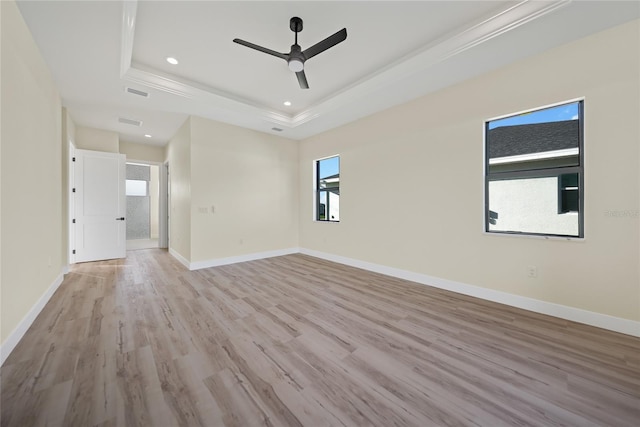 unfurnished room with a raised ceiling, ceiling fan, and light wood-type flooring