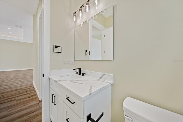 bathroom with vanity, toilet, and hardwood / wood-style floors