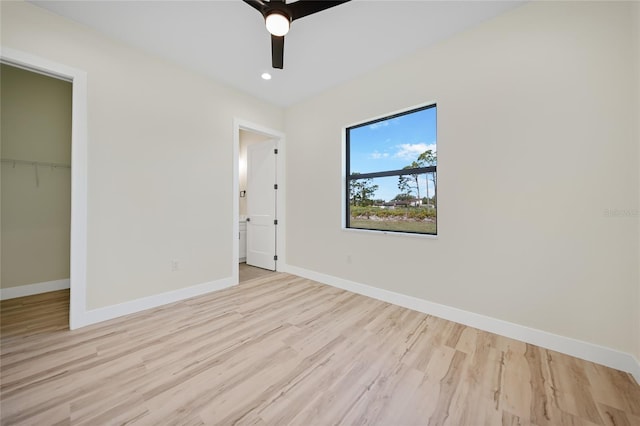 unfurnished bedroom featuring ceiling fan, a closet, light hardwood / wood-style flooring, and a walk in closet