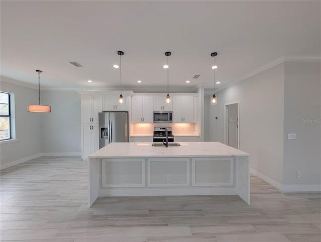 kitchen featuring decorative light fixtures, sink, white cabinets, stainless steel appliances, and a spacious island