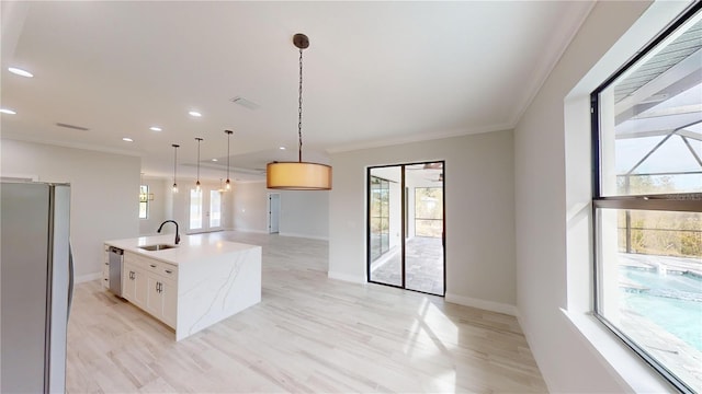 kitchen with sink, hanging light fixtures, stainless steel appliances, white cabinets, and a center island with sink