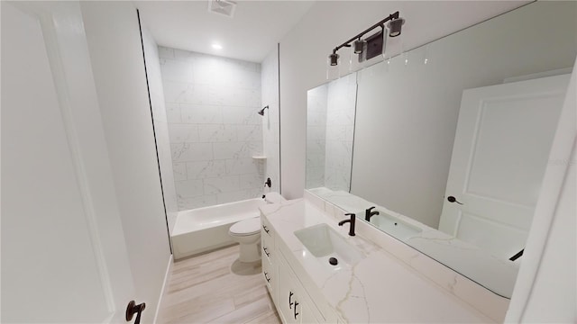 full bathroom with tiled shower / bath, hardwood / wood-style floors, vanity, and toilet