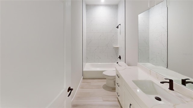 full bathroom with hardwood / wood-style flooring, tiled shower / bath, vanity, and toilet