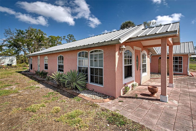 view of home's exterior with stucco siding, metal roof, and a patio