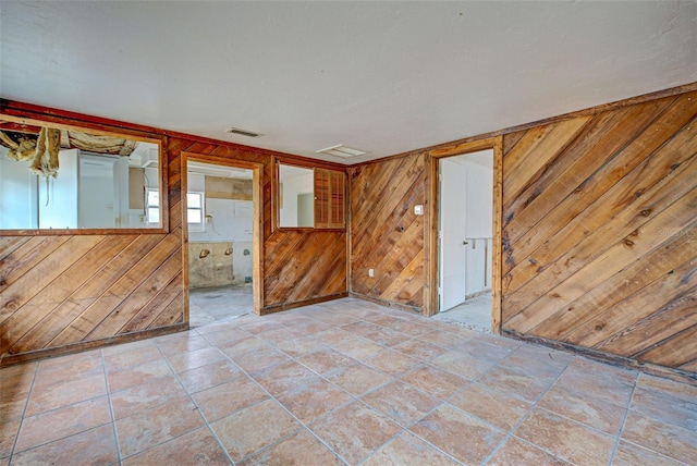 empty room with visible vents, wood walls, and light tile patterned floors