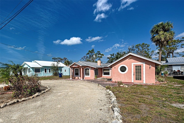 ranch-style home featuring gravel driveway and a chimney