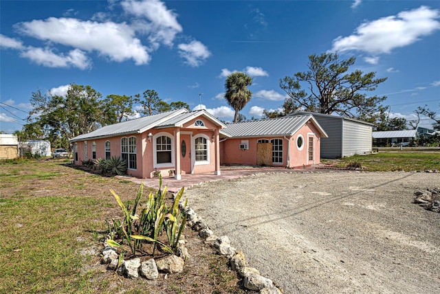 ranch-style home featuring metal roof, driveway, and stucco siding