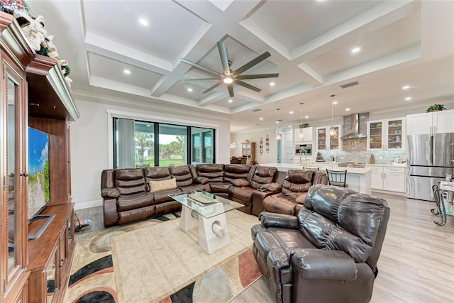 living room featuring coffered ceiling, beamed ceiling, ceiling fan, and light hardwood / wood-style flooring