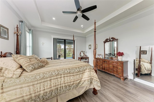 bedroom featuring light wood-type flooring, a tray ceiling, crown molding, ceiling fan, and access to outside