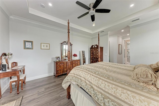 bedroom featuring wood-type flooring, crown molding, a tray ceiling, and ceiling fan