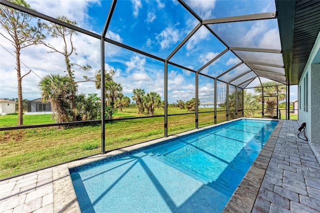 view of pool with a lawn, a patio, and a lanai