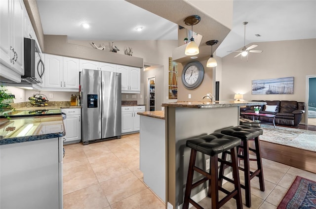 kitchen featuring white cabinetry, stainless steel appliances, a kitchen breakfast bar, light tile patterned flooring, and vaulted ceiling