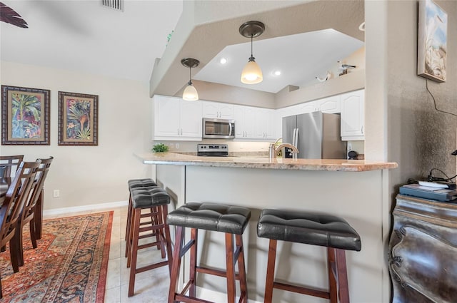 kitchen featuring light stone countertops, stainless steel appliances, kitchen peninsula, and white cabinets