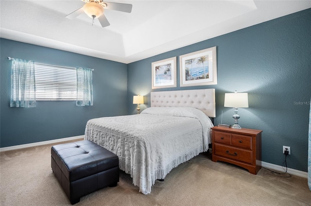 bedroom featuring ceiling fan, a tray ceiling, and carpet floors