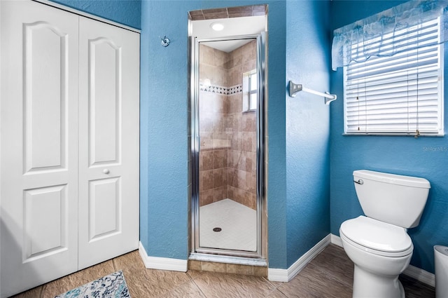 bathroom with plenty of natural light, a shower with door, and toilet