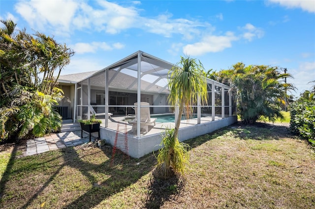 rear view of property with a yard, a patio, and glass enclosure