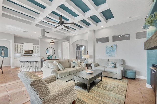 tiled living room with ceiling fan, coffered ceiling, beam ceiling, and a high ceiling