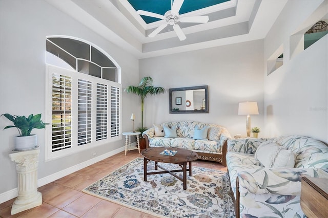 living room featuring tile patterned flooring, a raised ceiling, ceiling fan, and a high ceiling