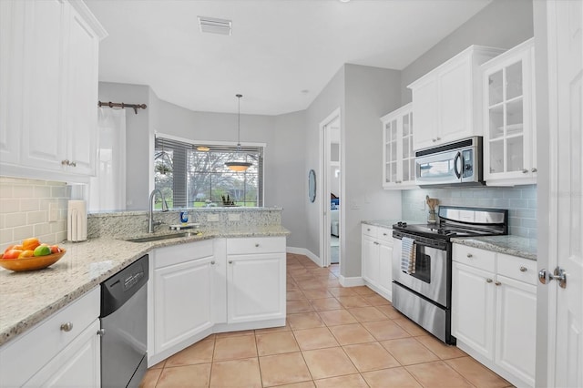 kitchen featuring decorative light fixtures, sink, white cabinets, light stone counters, and stainless steel appliances