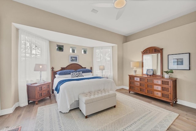 bedroom with multiple windows, wood-type flooring, and ceiling fan