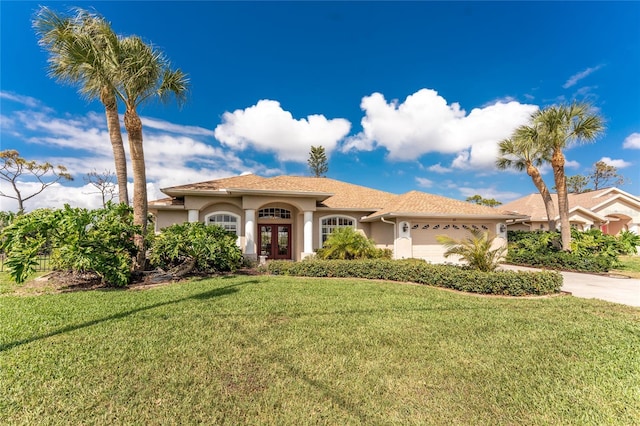 mediterranean / spanish-style home featuring a front lawn, french doors, and a garage