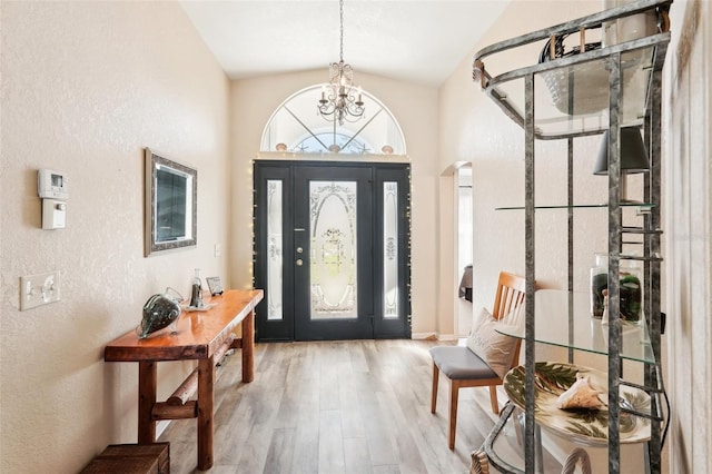 foyer with vaulted ceiling, a chandelier, and wood-type flooring