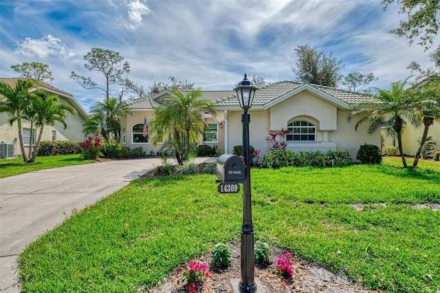 view of front of home featuring a tiled roof, a front yard, and stucco siding