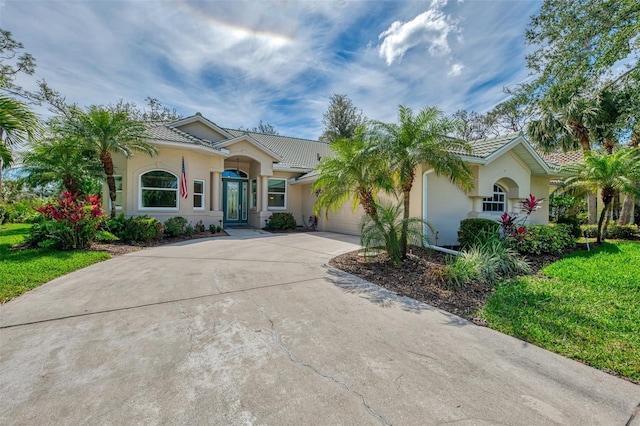 view of front of home with a garage, concrete driveway, a tiled roof, and stucco siding