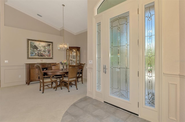 entrance foyer with crown molding, lofted ceiling, light colored carpet, a decorative wall, and an inviting chandelier