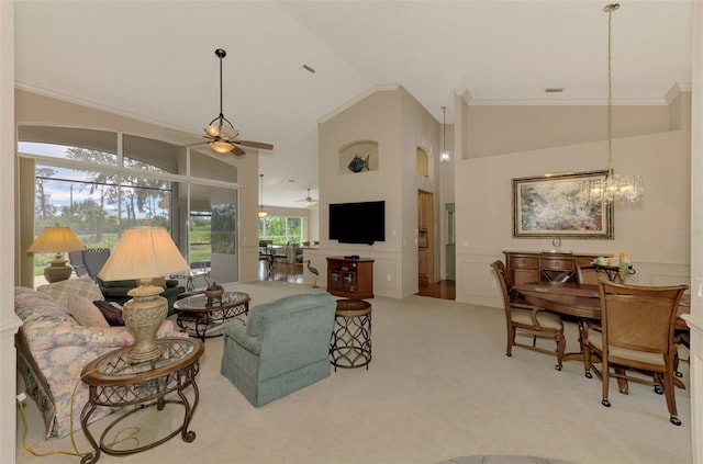 living room featuring a decorative wall, wainscoting, carpet flooring, high vaulted ceiling, and ceiling fan with notable chandelier