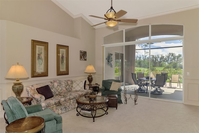 carpeted living room featuring a decorative wall, a towering ceiling, a ceiling fan, ornamental molding, and wainscoting