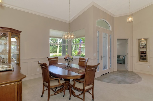 dining area with a wainscoted wall, light colored carpet, a decorative wall, ornamental molding, and a chandelier