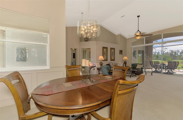 carpeted dining room featuring a decorative wall, ornamental molding, wainscoting, high vaulted ceiling, and ceiling fan with notable chandelier