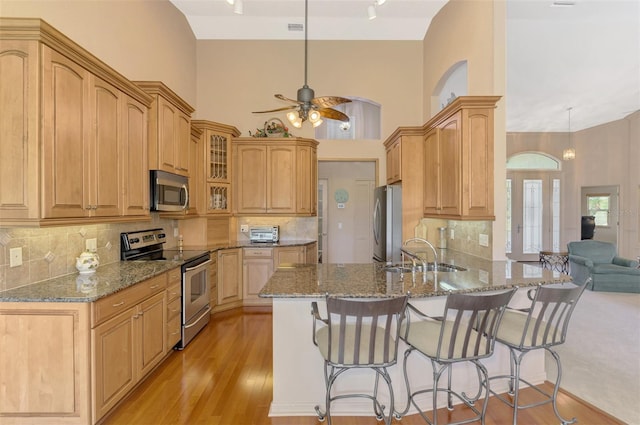 kitchen with stone countertops, appliances with stainless steel finishes, a breakfast bar, and a sink