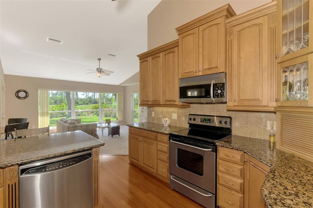 kitchen featuring lofted ceiling, visible vents, backsplash, appliances with stainless steel finishes, and open floor plan