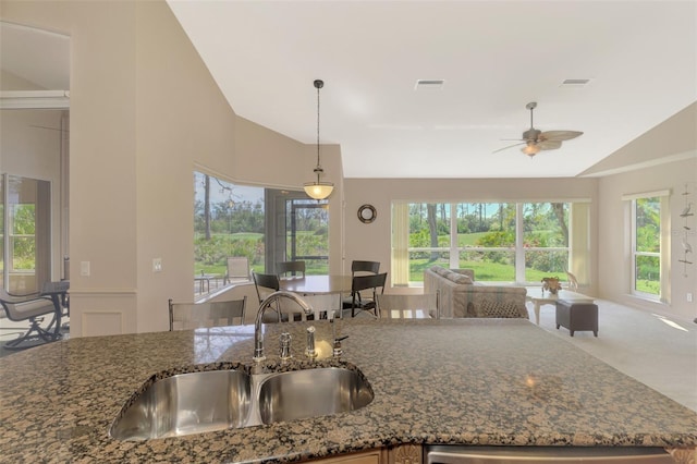 kitchen with visible vents, dark stone counters, open floor plan, pendant lighting, and a sink