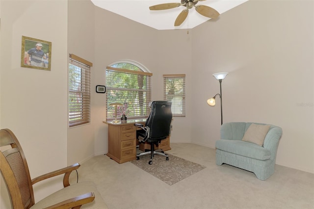 office area with a high ceiling, a ceiling fan, and light colored carpet