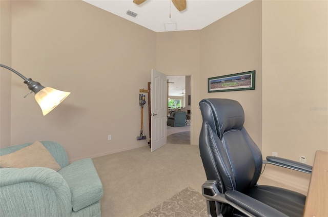 office featuring a ceiling fan, a towering ceiling, visible vents, and light colored carpet