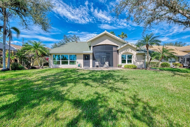 back of property featuring a sunroom, a tiled roof, a lawn, and stucco siding