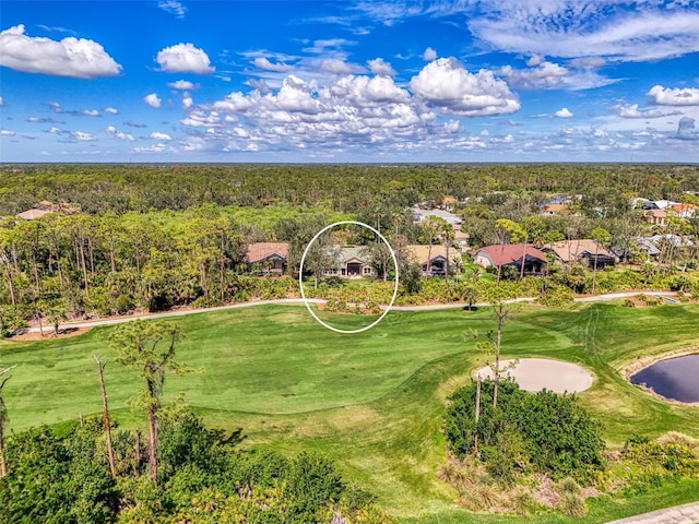 drone / aerial view featuring golf course view and a view of trees