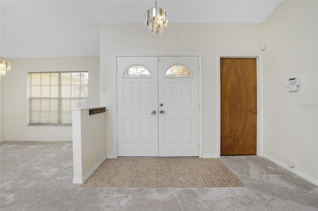 carpeted foyer entrance featuring vaulted ceiling and a chandelier