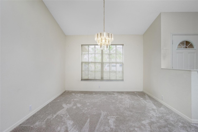 carpeted spare room with a chandelier and vaulted ceiling